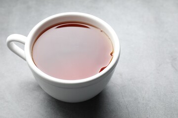 Refreshing black tea in cup on grey table, closeup