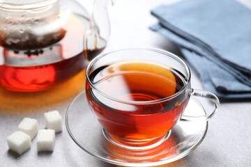 Aromatic black tea and sugar cubes on light table, closeup