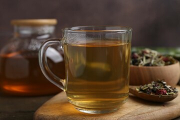 Delicious herbal tea and dry leaves on wooden table, closeup