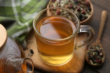 Delicious herbal tea and dry leaves on wooden table, closeup