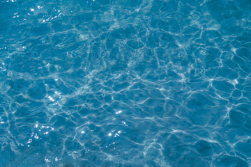 Fototapeta premium Overhead view of blue water surface abstract. Wave on moving water surface close up in the middle of the screen. Blue ocean water with waves background