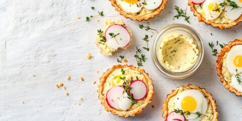 Tiny egg and vegetable appetizers with a dip. Eggs are nestled in toasted bread rounds, garnished with fresh herbs.