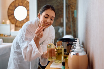 Young happy woman choosing aromatherapy oil at spa.