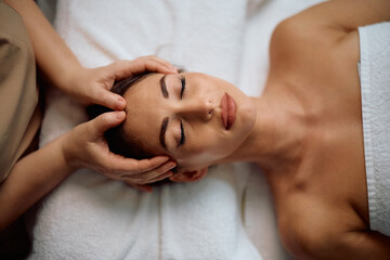 Young woman having head massage during beauty treatment at spa.