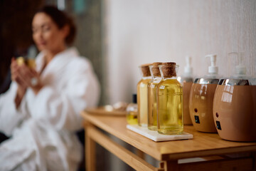 Close up of massage oils at spa with woman in background.