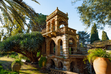 Brick tower in Villa Comunale di Taormina, Sicily, Italy, surrounded by lush Mediterranean...