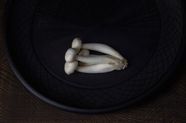 White bunapi mushrooms lying on black plate on wooden table