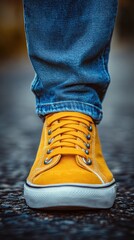 Close-Up of Yellow Sneakers and Jeans on a Pebbled Road
