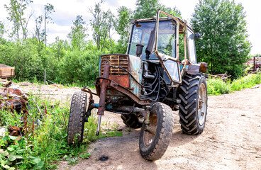 Naklejka premium Old rusty wheeled tractor at the village in summer