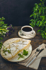 Delicious apple strudel with icing sugar served on a plate with coffee