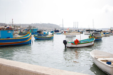 Obraz premium Colorful traditional maltese luzzu boats moored near Marsaxlokk fishers village on Malta