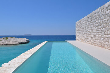Fototapeta premium A pool with a wall of stone and a body of water in the background