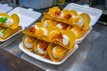 Mouth-watering image of traditional Thai crispy pancakes with sweet whipped cream and colorful filling. It is perfect for illustrating street food culture and its seductive flavors.