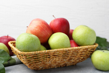 Fresh ripe apples in wicker basket on grey table, closeup
