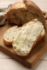Fresh bread with butter on light wooden table, closeup