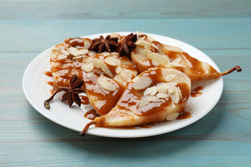 Delicious pears with caramel sauce, almond flakes and anise stars on light blue wooden table, closeup