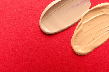 Samples of different foundations on red background, top view. Space for text
