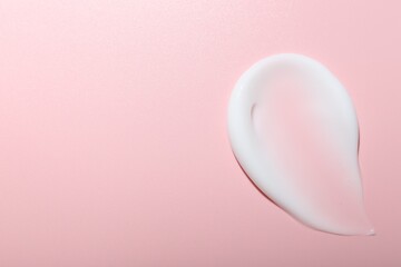 Cream sample on pink background, top view. Space for text