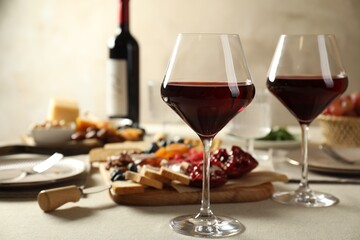 Red wine and different snacks served on light grey table
