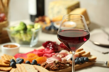 Red wine and different snacks served on table, closeup
