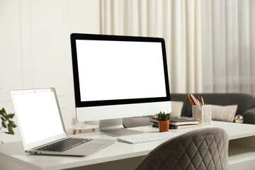 Fototapeta premium Modern workplace with computer and laptop on white desk indoors