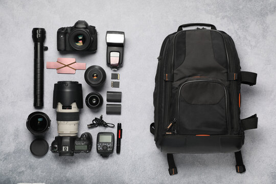 Professional photographer's equipment and backpack on light background, flat lay