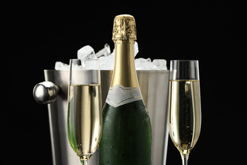Bottle of sparkling wine, glasses and cooler bucket on black background, closeup © New Africa