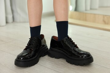 Little girl wearing oversized shoes indoors, closeup
