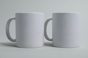 Two blank mugs for branding on light grey background. Mockup for design