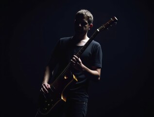 Fototapeta premium Musician holding electric guitar illuminated with moody lighting and dark background