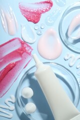 Cream, scrub and gel samples on light blue background, flat lay. Stylish presentation with tube of skincare product