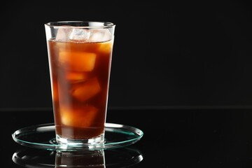 Refreshing iced coffee in glass on black mirror surface, closeup. Space for text