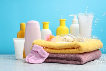 Baby cosmetic products, socks, bath accessories and flying bubbles on grey textured table against...