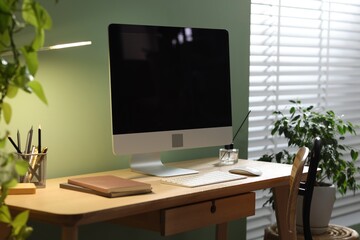 Comfortable workplace with computer and stationery on wooden desk in home office