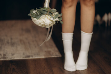 Close-up of legs in white socks and a wedding bouquet