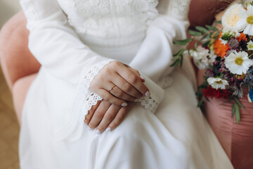 Close-up of the bride's hands on a white wedding dress