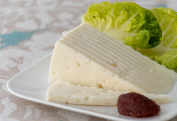 Spanish hard manchego, cow, sheep and goat cheese served for breakfast with green salad leaves and Membrillo quince cheese close up