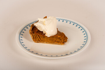 Slice of delicious pumpkin pie on plate with whipped topping.