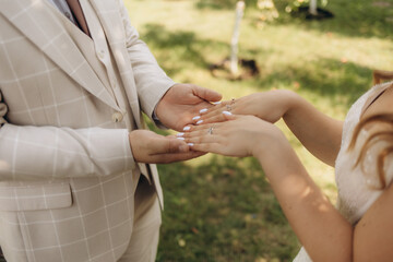 The bride and groom hold hands on their wedding day and put their rings on each other in love on a...