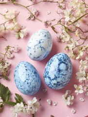 Three blue marble Easter eggs with a blurred background of pink flowers and green foliage, suggesting springtime and holiday celebration.
