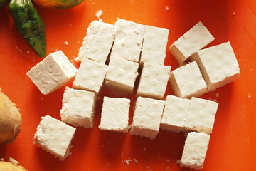 Freshly cut tofu cubes on vibrant orange cutting board