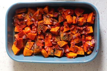 Sheet pan with pieces of butternut squash, onion, herbs and spices. Preparing pumpkin for a roast....