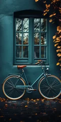 Fototapete Charming vintage bicycle leaning against a teal wall, framed by autumn leaves, evoking a serene, picturesque urban vibe perfect for lifestyle and travel themes. © deounix