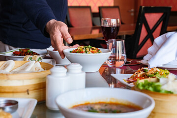 A close-up shot of a waiter serving a vibrant stir-fry dish at Asian restaurant.