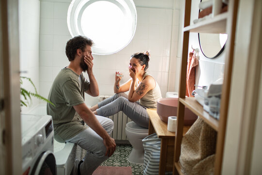 Couple celebrating positive pregnancy test in bathroom
