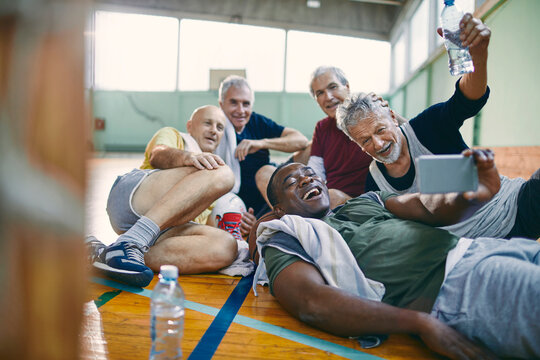 Senior men taking group selfie after basketball game - Powered by Adobe