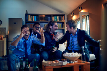 Diverse business colleagues watching sports game with beer at home after work