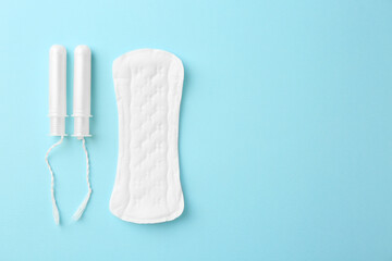 Menstrual pad and tampons on light blue background, top view. Space for text