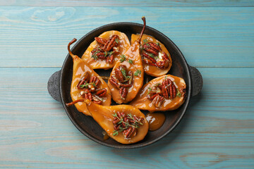 Delicious pears with caramel sauce, pecan nuts and thyme on light blue wooden table, top view