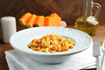 Delicious pumpkin risotto served on wooden table, closeup